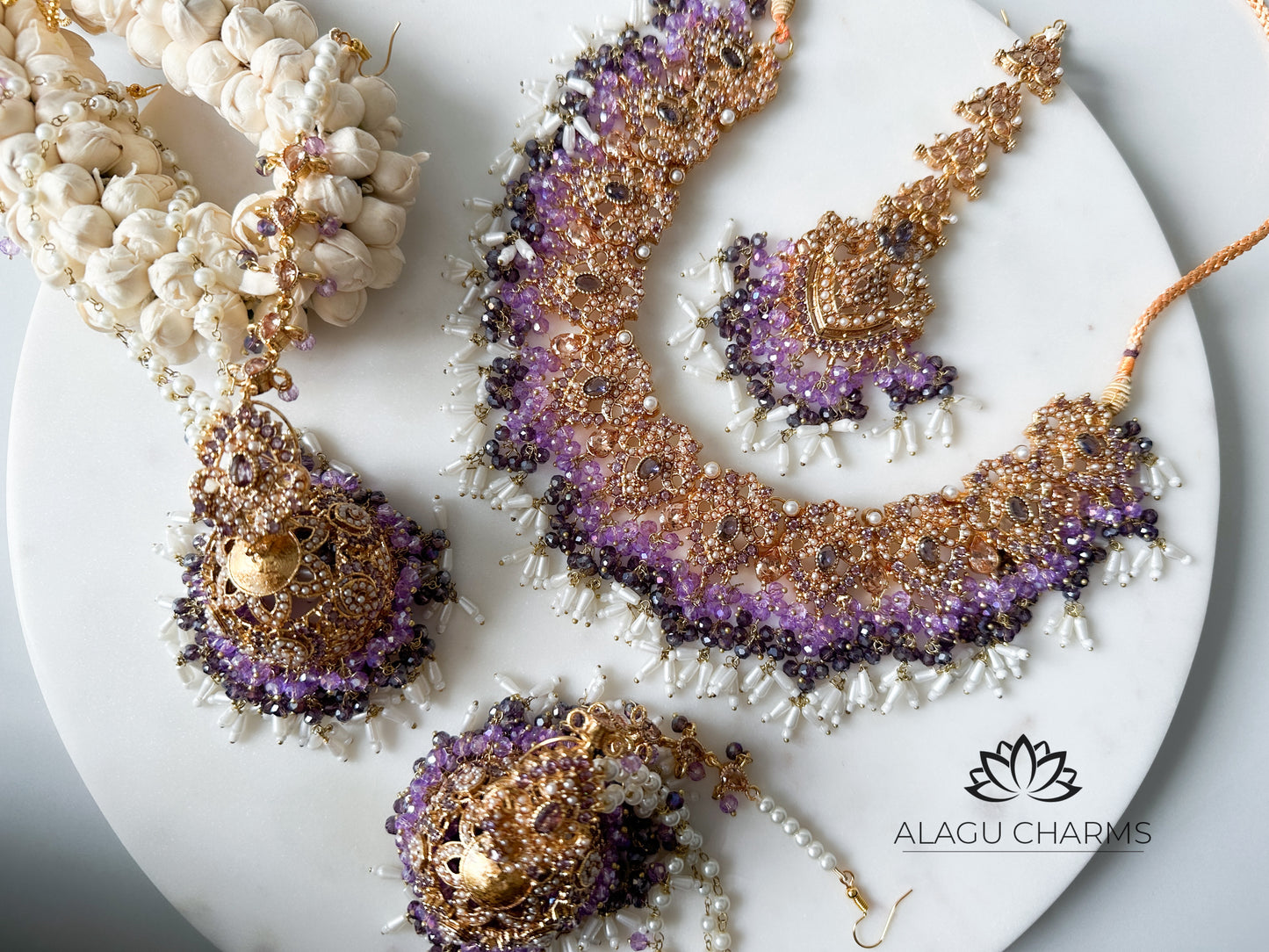 Luxurious Pakistani-style bridal set featuring ornate gold-tone jhumka earrings and matching tikka, embellished with deep purple gemstones and detailed filigree for an elegant ceremonial look. Pakistani jewellery in Germany