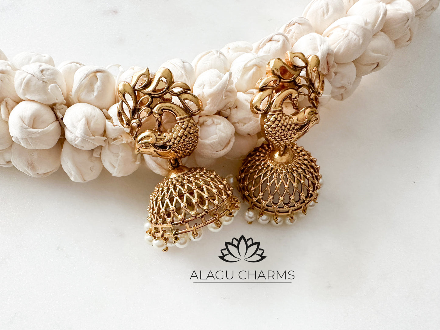 Antique-style gold jhumka earrings featuring an intricate peacock motif at the top, ornate filigree work on the bell-shaped dangler, and delicate gold bead dangles along the hem. temple jhumka online shop, Germany, Europe