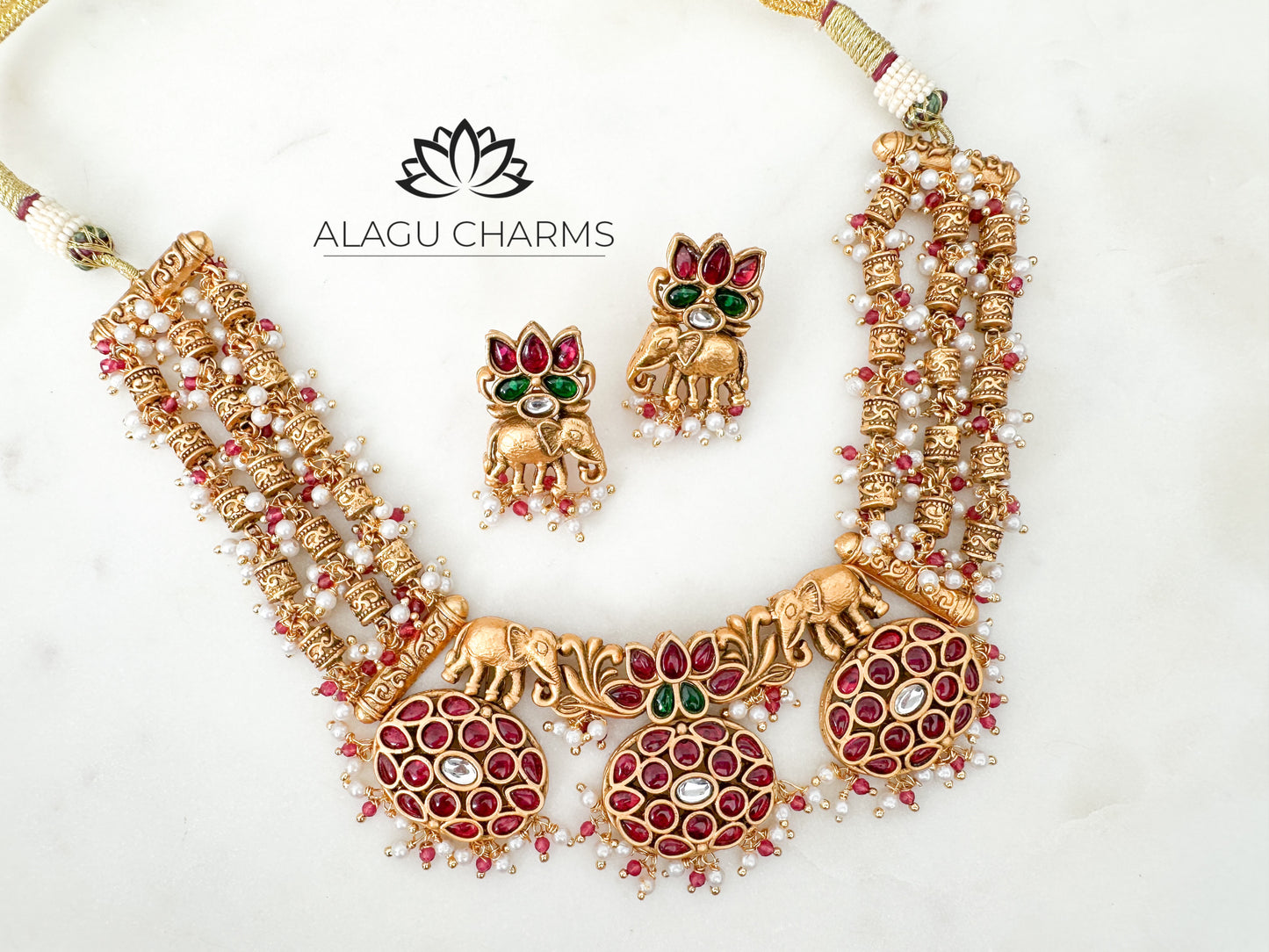 Antique gold-tone neck piece featuring elephant motifs, adorned with red and green Kemp stones, displayed on a neutral background. temple jewelry in Germany, temple necklace, southindian jewellery