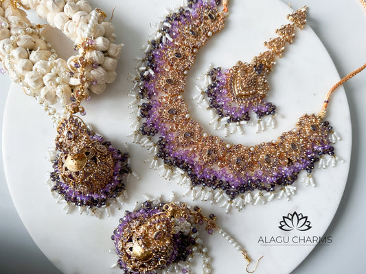 Luxurious Pakistani-style bridal set featuring ornate gold-tone jhumka earrings and matching tikka, embellished with deep purple gemstones and detailed filigree for an elegant ceremonial look. Pakistani jewellery in Germany